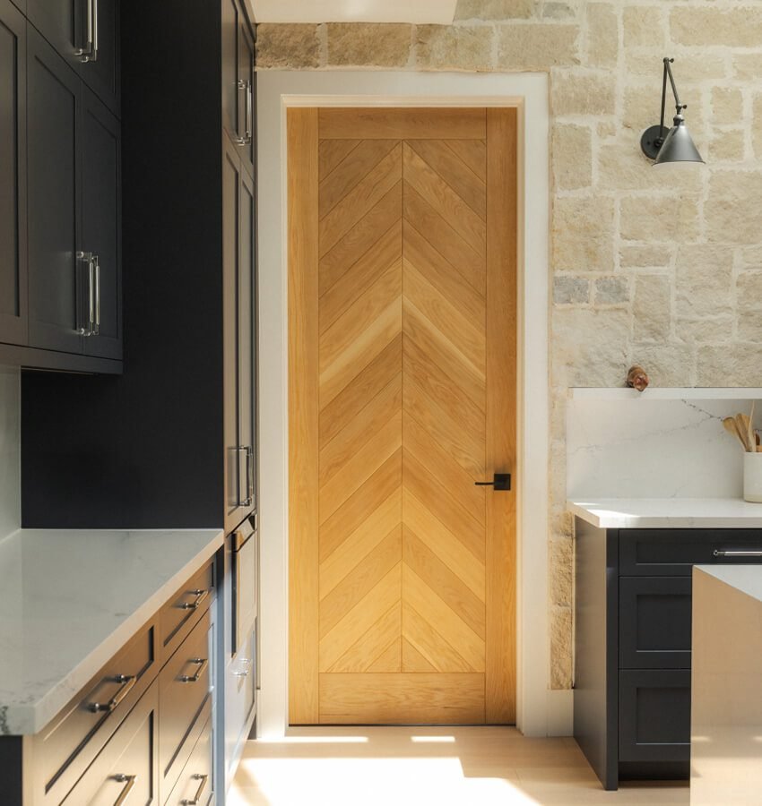 Kitchen island with stone wall and chevron oak door