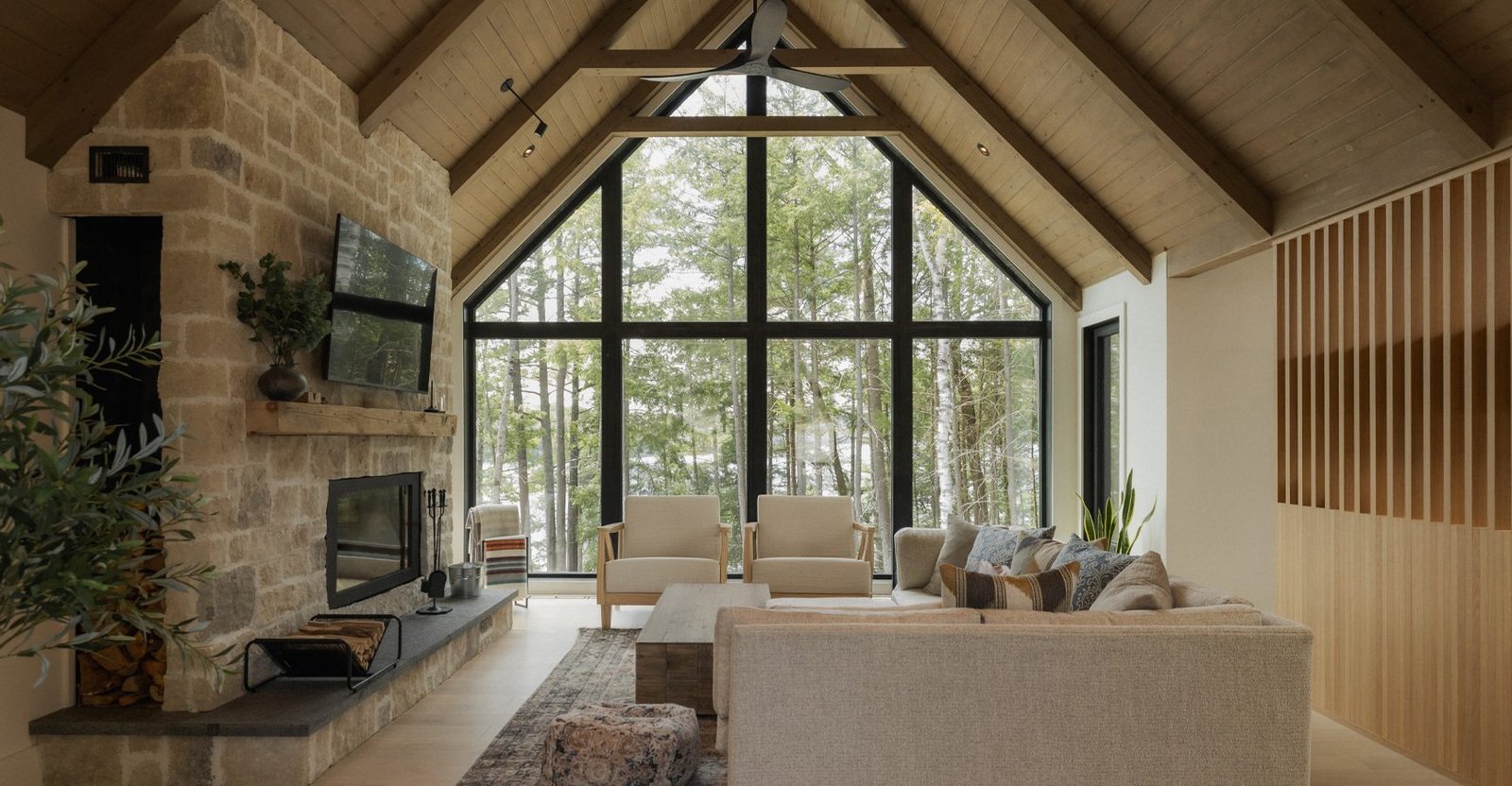 Vaulted, window-walled living room with stone fireplace at The Crag